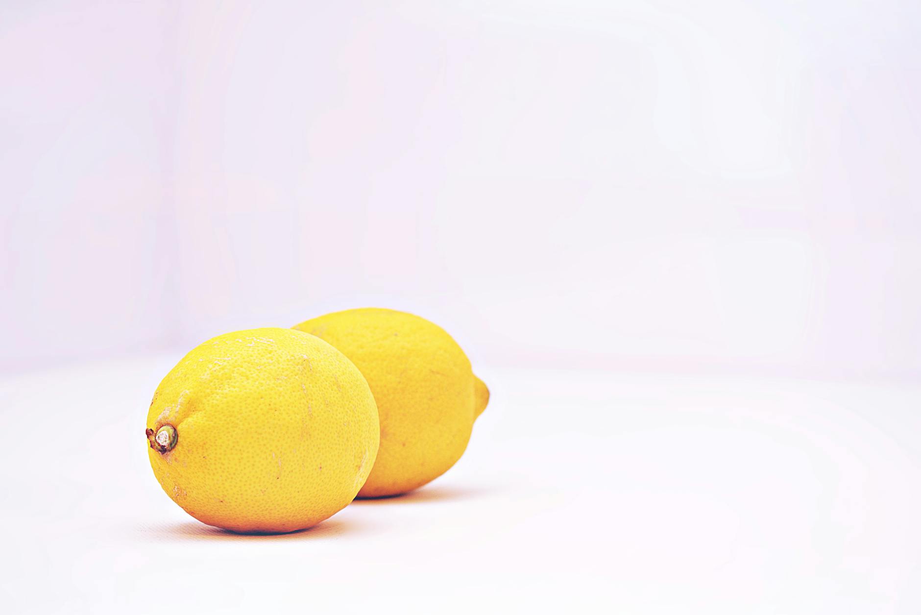 Hand holding a fresh lemon against a bright yellow background, representing vibrant sensuality and youthful vitality.