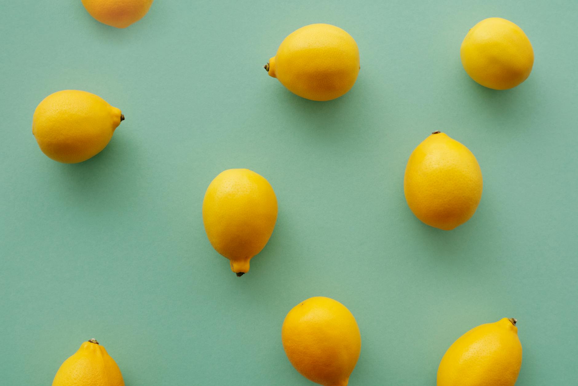 Hand holding a fresh lemon against a bright yellow background, symbolizing renewal and exploration
