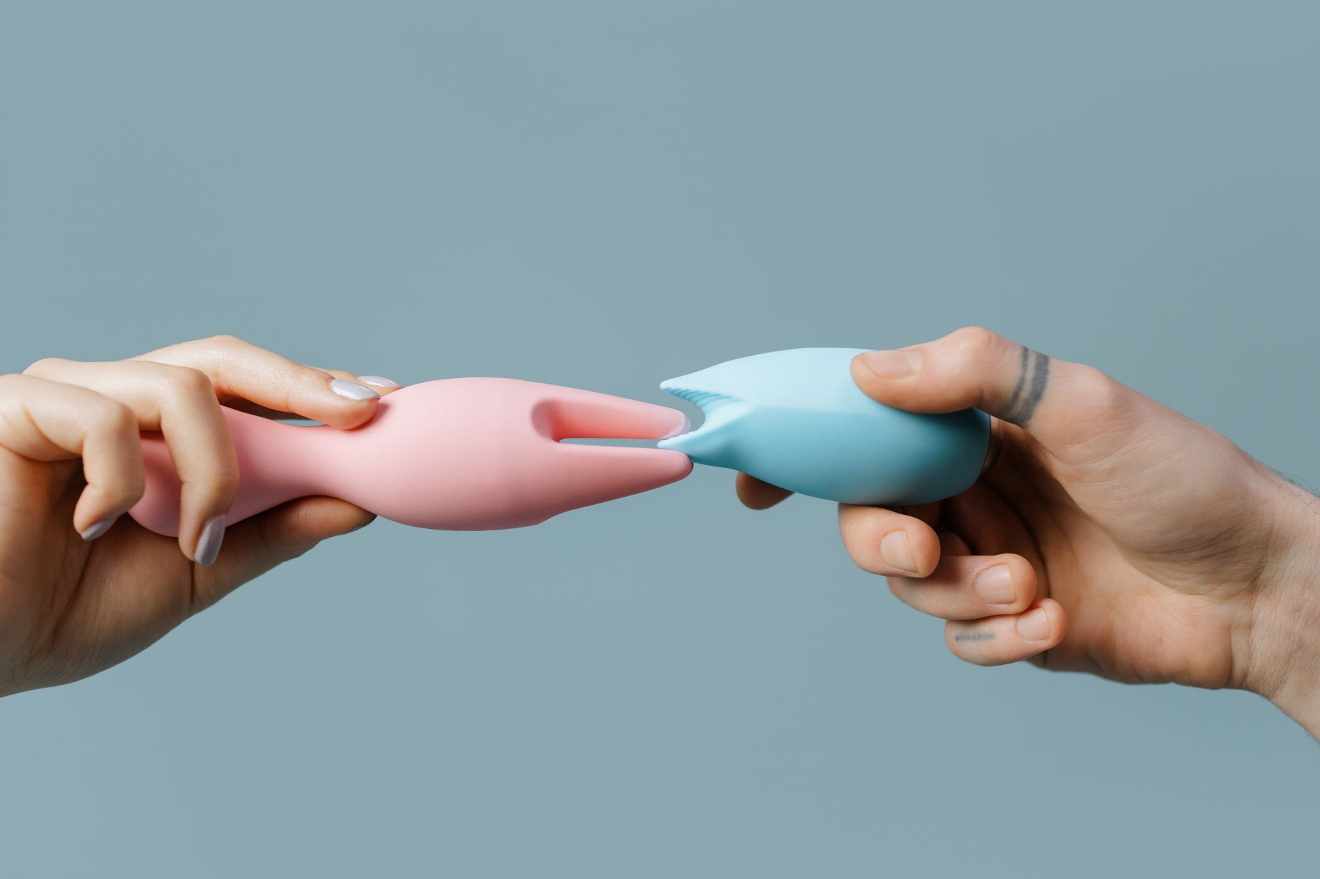Hands holding colorful silicone toys on a soft background, representing pleasure exploration