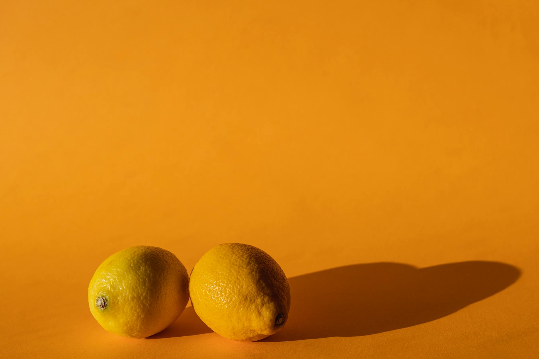 Ripe vivid lemons arranged on a bright yellow background in natural daylight